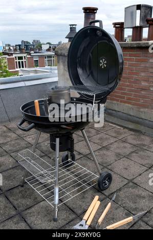 Black Compact Holzkohlegrill Wasserkocher mit gebratenem Gemüse auf der Terrasse, im Garten oder auf dem Dach. Stockfoto