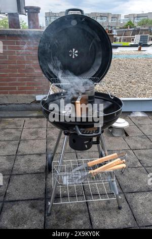 Black Compact Holzkohlegrill Wasserkocher mit gebratenem Gemüse auf der Terrasse, im Garten oder auf dem Dach. Stockfoto