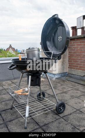 Black Compact Holzkohlegrill Wasserkocher mit gebratenem Gemüse auf der Terrasse, im Garten oder auf dem Dach. Stockfoto