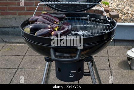 Black Compact Holzkohlegrill Wasserkocher mit gebratenem Gemüse auf der Terrasse, im Garten oder auf dem Dach. Stockfoto