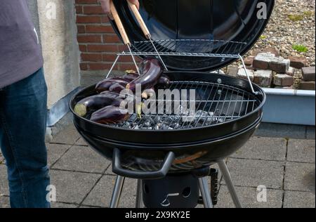 Black Compact Holzkohlegrill Wasserkocher mit gebratenem Gemüse auf der Terrasse, im Garten oder auf dem Dach. Stockfoto