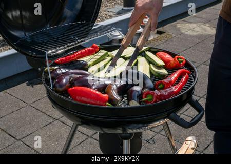 Black Compact Holzkohlegrill Wasserkocher mit gebratenem Gemüse auf der Terrasse, im Garten oder auf dem Dach. Stockfoto