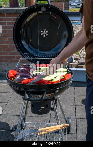 Black Compact Holzkohlegrill Wasserkocher mit gebratenem Gemüse auf der Terrasse, im Garten oder auf dem Dach. Stockfoto