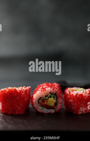 Japanisches Essen: Sushi, kalifornische Brötchen mit Lachs, Avocado, Tobiko Kaviar, Gurke. Schwarzer Hintergrund Stockfoto