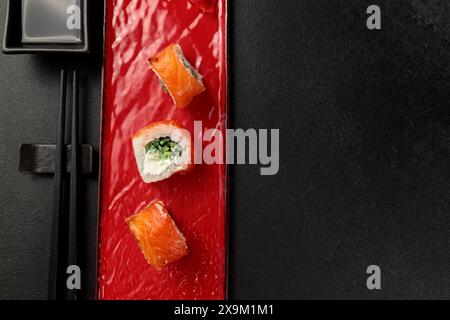 Eine klassische Philadelphia-Rolle mit Garnelen und Lachs steht vor einem eleganten schwarzen Hintergrund im Mittelpunkt. Es ist eine köstliche Darstellung von Ja Stockfoto