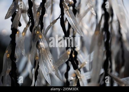 Federförmige Außenleuchten. Außendekoration aus Kunststoff mit warmgelben Glühbirnen. Stockfoto