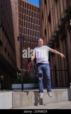 Alter Geschäftsmann Kaukasischer Angestellter älterer Geschäftsmann Angestellter tanzend Treppen hinunter Büro in der Stadt Glückliche gute Laune Erfolg Sprung Stockfoto