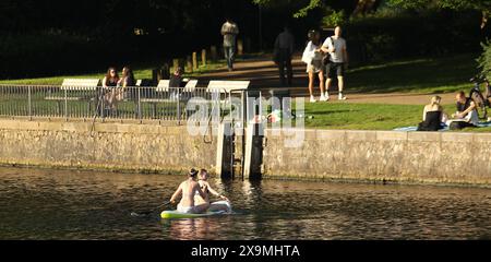 Zwei junge Frauen sitzen auf einem Paddleboard und fahren bei Temperaturen um die 25 Grad auf einem Alsterkanal entlang. Eppendorf Hamburg *** zwei junge Frauen sitzen auf einem Paddleboard und reiten bei Temperaturen von rund 25 Grad auf einem Alsterkanal in Eppendorf Hamburg Stockfoto