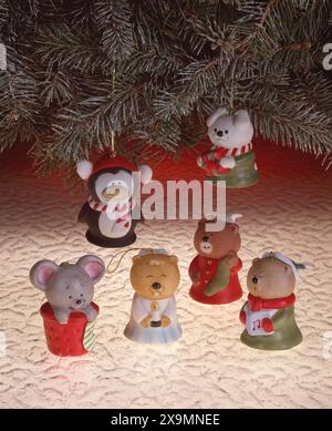 Festliche Weihnachtsdekorationen aus Keramik mit niedlichen Tieren unter immergrünen Zweigen, warm beleuchtete Weihnachtsdekorationsszene mit gemütlichem saisonalem Charme Stockfoto