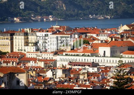 Blick vom Stadtteil Graca in Lissabon auf die Häuser und Dächer des Stadtteils Baixa mit dem Fluss Tejo im Hintergrund am milden Morgen l Stockfoto