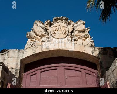 Detailliert dekorierter Bogengang mit einem Wappen mit historischen Motiven unter einem klaren blauen Himmel, die Stadt mdina auf der Insel malta mit Stockfoto