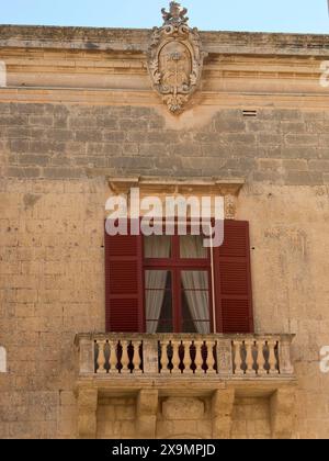 Historische Fassade mit roten Fensterläden und kleinem Steinbalkon, die Stadt mdina auf der Insel malta mit historischen Häusern und bunten Balkonen Stockfoto