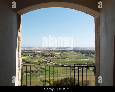 Panoramablick auf eine weite Landschaft und eine Stadt, gesehen durch einen Steinbogen, die Stadt mdina auf der Insel malta mit historischen Häusern, farbenfroh Stockfoto