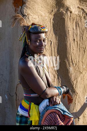 Hakaona-Frau mit traditionellem Kapapo-Haar und Haarschmuck mit Straußenfedern und farbenfrohen Halsketten, Porträt. Im Morgenlicht Stockfoto