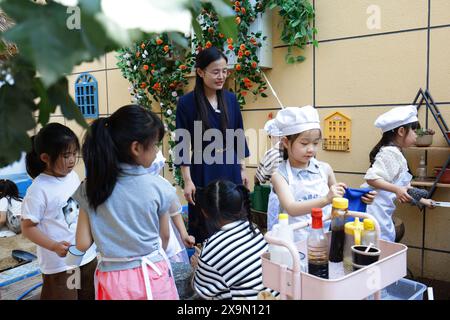 Xuzhou, chinesische Provinz Jiangsu. Mai 2024. Zhang Qian (C), Direktor des Xuhai Road Kindergartens, besucht am 23. Mai 2024 einen Kochkurs mit Kindern im Kindergarten in Xuzhou, ostchinesischer Provinz Jiangsu. In der Stadt Xuzhou produziert der Xuhai Road Kindergarten eine unkonventionelle Symphonie mit dem rhythmischen Zerkleinern von Gemüse, dem beruhigenden Brötchen und dem sanften Mahlen der Sojabohnenmilch. UM MIT „China Focus: Kindergarten-„Köche“ lösen Diskussionen über praktische Bildung im Vorschulalter aus“ Credit: Zhao Jiulong/Xinhua/Alamy Live News Stockfoto