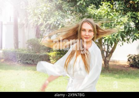 Ein glückliches Mädchen in einem weißen Kleid dreht sich im Garten Stockfoto