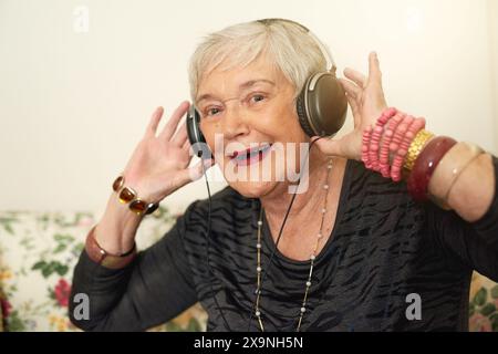 Ältere Frau, Porträt und Kopfhörer zu Hause mit Musik für den Ruhestand, Audio-Playlist und Streaming für Online-Radio. Senior Lady, glücklich und hören Sie zu Stockfoto