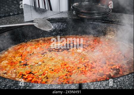 Karotten, Kichererbsen und Rosinen werden in einem Kessel gekocht, um traditionelle usbekische Pilaw in der Küche des Restaurants in Taschkent, Usbekistan, zu kochen Stockfoto