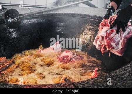 In der Küche des Restaurants in Usbekistan in Taschkent kocht der männliche Koch Rindfleisch in einem Kessel für das traditionelle arabische usbekische Pilaw Stockfoto