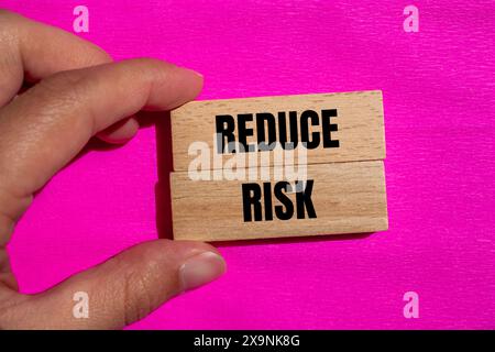 Wörter auf Holzblöcken mit rosafarbenem Hintergrund reduzieren das Risiko. Symbol für die konzeptionelle Risikoreduzierung. Kopierbereich. Stockfoto