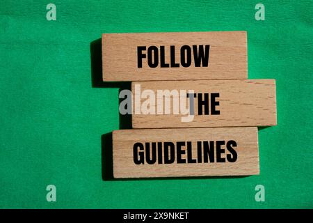 Folgen Sie den Hinweisen auf Holzblöcken mit grünem Hintergrund. Konzeptionell Befolgen Sie das Richtliniensymbol. Kopierbereich. Stockfoto