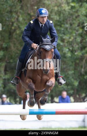19. Mai 2024, Mafra, Portugal - Wettkampf in der Militärakademie - Mann im blauen Anzug reitet auf einem braunen Pferd über einen Sprung Stockfoto
