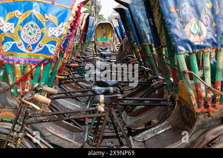 Dhaka, Dhaka, Bangladesch. Juni 2024. Ordentlich geparkte Rikschas in einer Rikscha-Garage in Dhaka, Bangladesch. Die Rikschas von Dhaka sind ein lebendiges Symbol der belebten Straßen der Stadt, die mit farbenfrohen Kunstwerken und Designs verziert sind. Trotz der rasanten Urbanisierung und der zunehmenden Verbreitung motorisierter Fahrzeuge bieten diese pedalbetriebenen Fahrzeuge eine bequeme und umweltfreundliche Alternative für die Navigation durch die überlasteten Straßen der Stadt. (Kreditbild: © Joy Saha/ZUMA Press Wire) NUR REDAKTIONELLE VERWENDUNG! Nicht für kommerzielle ZWECKE! Stockfoto