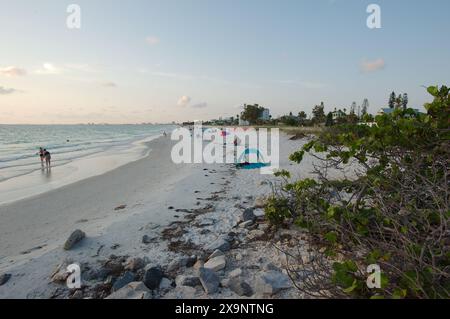 Weitwinkelblick auf den Pass-a-Grille Strand in St. Pete Beach Florida mit Blick nach Norden. Felsen und mehrere Leute, die im Sand und im Wasser spazieren, nahe am Set Stockfoto