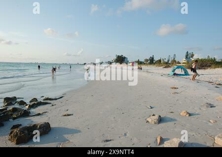 Weitwinkelblick auf den Pass-a-Grille Strand in St. Pete Beach Florida mit Blick nach Norden. Felsen und mehrere Leute, die im Sand und im Wasser spazieren, nahe am Set Stockfoto