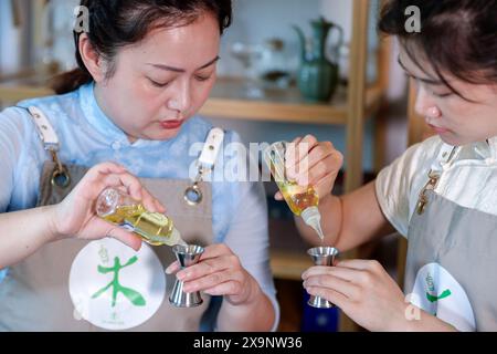 (240602) – HUANGSHAN, 2. Juni 2024 (Xinhua) – Wang Sun (L) gibt ihrem Lehrling Anweisungen an der Demingshe, einer Teekunst-Berufsschule in Huangshan, ostchinesischer Provinz Anhui, 23. Mai 2024. Wang Sun ist der Gründer von Demingshe, einer Teekunst-Berufsschule in Huangshan. Huangshan City ist der Ursprungsort mehrerer berühmter Tees, darunter Huangshan Maofeng, Taiping Houkui und Keemun Schwarztee, und rühmt sich einer langen Geschichte des Teetrinkens. Als Pionier bei der Entwicklung innovativer Teezubereitungsfähigkeiten und alternativer Methoden des Teetrinkens begann Wang mit der Forschung Stockfoto