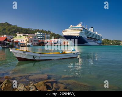 St. Lucia - Januar 30 2024: Im Hafen von Castries auf der Insel St. Lucia in der Karibik ein kleines Fischerboot im Vordergrund mit der Marella Voyager cr Stockfoto