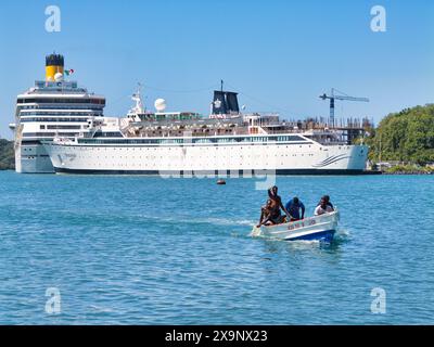 St. Lucia - Januar 30 2024: Einheimische Fischer machen sich auf den Heimweg über die Bucht von Castries auf St. Lucia in der Karibik, mit Kreuzfahrtschiffen, die an Point ankern Stockfoto