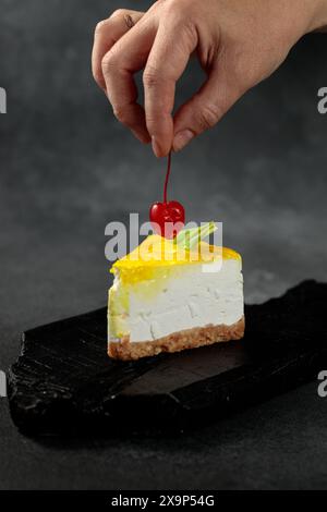 Zitronenkäsekuchen mit Kirschen vor einem eleganten schwarzen Hintergrund. Ein köstliches visuelles Vergnügen, perfekt für Dessertliebhaber und kulinarische Präsente Stockfoto