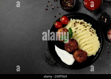 Gebratene Schnitzel mit Kartoffelpüree, Tomaten und Kräutern, elegant auf einer schwarzen Schale vor dunklem Hintergrund. Perfekt für die Präsentation von Hearty com Stockfoto