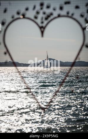 Segelyacht auf dem Meer bei Sonnenuntergang durch herzförmige Dekoration Stockfoto