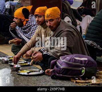 Gruppe junger sikh-Männer, die in einer Gemeinschaftsküche in einer Gurdwara essen Stockfoto