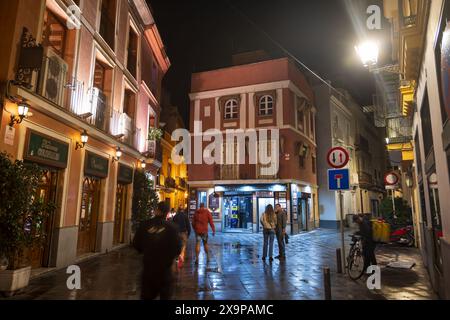 Sevilla, Andalusien, Spanien - 23. Oktober 2023 - Nacht in der Altstadt nach dem Regen mit dem Restaurant Taberna Coloniales auf der linken Seite. Stockfoto