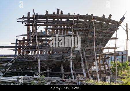 Verlassene Schiffsstruktur mit verwitterten Balken und karger Landschaft Stockfoto