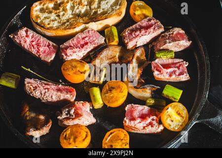 Thunfisch wird in einer gusseisernen Pfanne mit Kirschtomaten, Spargel, Speck und Toast gebraten. Hochwertige Fotos Stockfoto