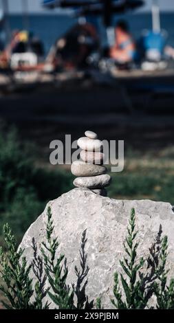 Steinpyramide auf dem Hintergrund des Strandes mit Urlaubern. Stockfoto