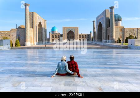 Junges Touristenpaar auf Registan, einem alten öffentlichen Platz im Herzen der antiken Stadt Samarkand, Usbekistan. Übersetzung: Im Namen von Stockfoto
