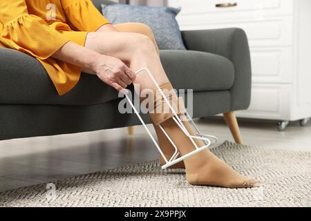 Frau in Kompressionsstrumpfhosen mit donner im Wohnzimmer, Nahaufnahme. Varizenprophylaxe Stockfoto