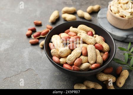 Frische ungeschälte Erdnüsse in der Schüssel auf grauem Tisch Stockfoto