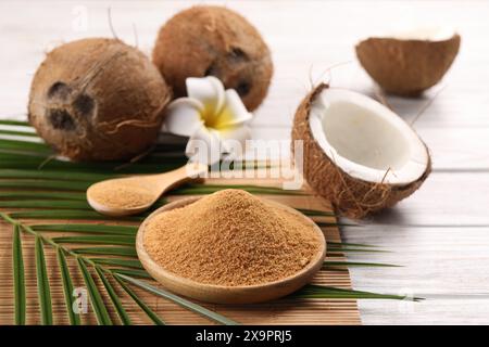 Kokoszucker, Palmblätter, Früchte und Bambusmatte auf rustikalem Holztisch, Nahaufnahme Stockfoto
