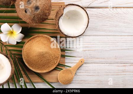 Kokosnusszucker, Palmblätter, Früchte und Bambusmatte auf rustikalem Holztisch, flache Ladefläche. Leerzeichen für Text Stockfoto