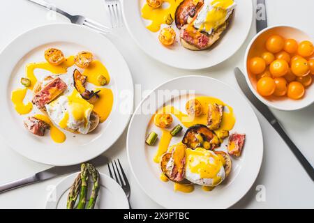 Ei Benedikt mit Thunfisch und Spargel auf einem weißen Tisch. Für drei Personen. Konzept: Ein leckeres und gesundes Familienfrühstück. Ausgewählter Fokus. Hallo Stockfoto