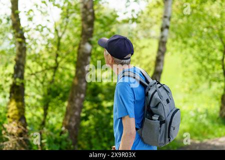 Senior Mann mit Rucksack, der im Wald wandert. Aktiver Seniorenstil. Stockfoto