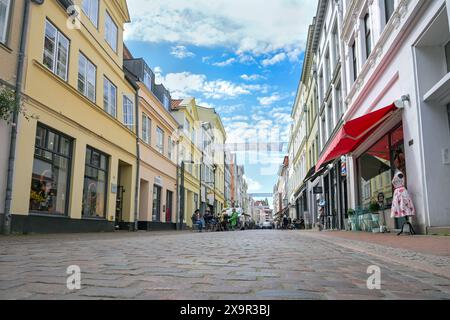 Lübeck, Deutschland, 30. Mai 2024: Huxsstraße, Kopfsteinpflasterstraße mit Geschäften und Restaurants in der historischen Altstadt an einem sonnigen Tag, berühmte Tour Stockfoto