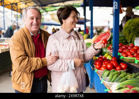 Ältere Männer und Frauen kaufen Tomaten auf einem freien Markt Stockfoto