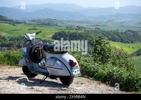 Eine traditionelle vespa parkt an einem Aussichtspunkt mit Blick auf traditionelle toskanische Felder, Landschaft und Landschaft in der Nähe der historischen Stadt Volterra. Stockfoto